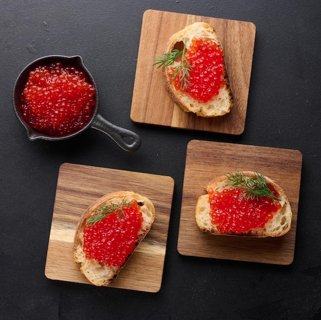 Roter Kaviar auf Scheiben weißem Weizenbrot auf einem schwarzen Tisch Konzept der Luxus- und Gourmetküche Top-View