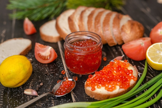 Roter Kaviar und andere Produkte auf einem dunklen Tisch
