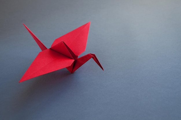 Foto roter kran origami aus papier isoliert auf grauem hintergrund