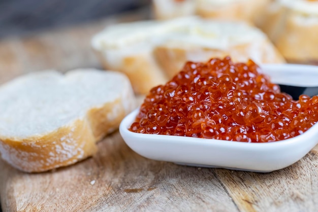 Roter Lachs- oder Forellenkaviar mit weißem Baguette und Butter zur Herstellung von Sandwiches mit Laibbutter und echtem roten Kaviar