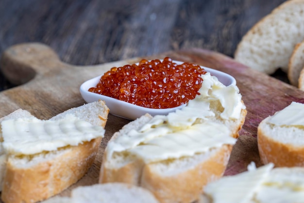 Roter Lachs- oder Forellenkaviar mit weißem Baguette und Butter zur Herstellung von Sandwiches mit Laibbutter und echtem roten Kaviar