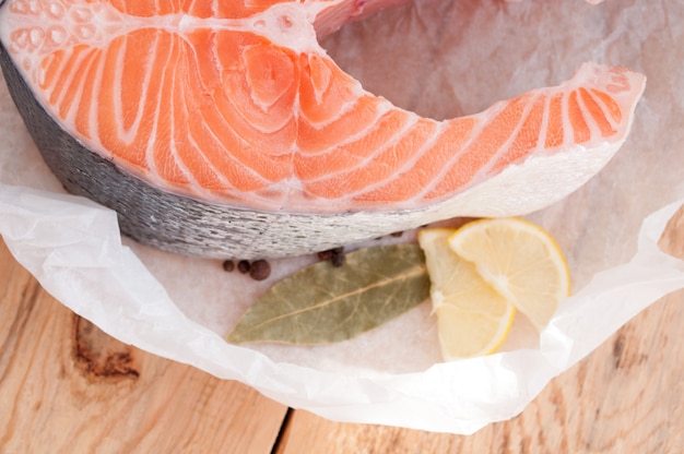 Roter Lachssteak roter Fisch und Gewürze auf Holztisch. Draufsicht