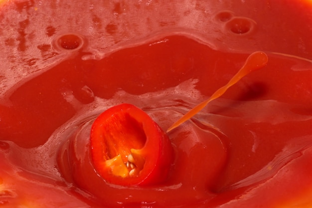 Roter Lebensmittelgeschäfthintergrund von Tomatensaft mit Paprikaspritzennahaufnahme