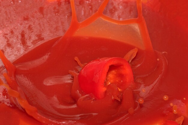 Roter Lebensmittelgeschäfthintergrund von Tomatensaft mit Paprikaspritzennahaufnahme