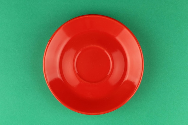 Roter leerer Teller auf grünem Hintergrund Minimalismus
