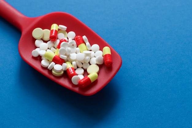 Roter Löffel mit pharmazeutischen Medizinpillen, -tabletten und -kapseln mit Kopienraum