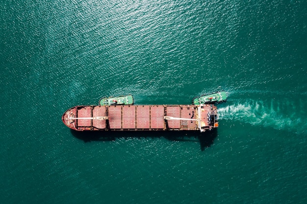 Roter Ölschiffstank und Schlepper, der auf grünem Meer segelt, fotografieren Luftaufnahmen aus Drohnensicht
