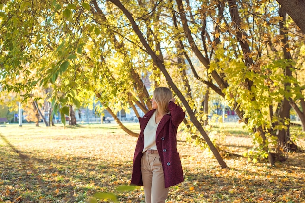 Roter mantel der frau, der im herbstpark steht