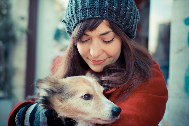 roter Mantel der schönen Frau, der den Hund umarmt