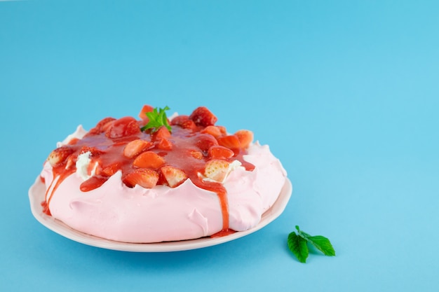 Roter Obstkuchen Pavlova auf einem blauen Tisch. Gebäckkonzept.