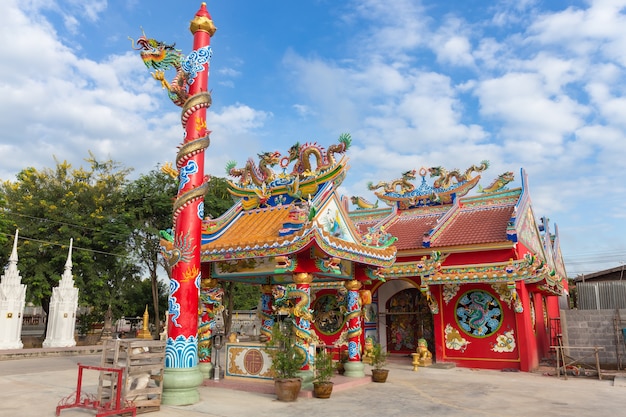 Roter öffentlicher Schrein mit goldener Drachestatue in der chinesischen Art auf Hintergrund des blauen Himmels bei Thailand