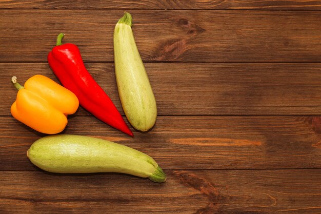 Roter Paprika Kapi mit gelbem Gemüsepaprika und Zucchini auf einem hölzernen Hintergrundraum für Text