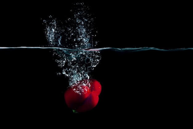 Roter Pfeffer in Wasser mit Spritzern. Gemischte Medien