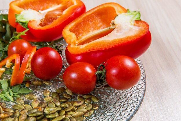 Roter Pfeffer mit Tomatenkirsche und -samen in hellem Holztisch der Glasplatte n. Zutaten in der Platte