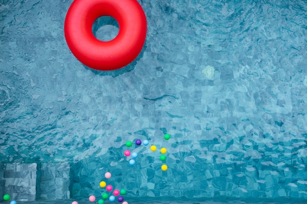 Roter Poolfloss, Ring, der in einen erneuernden blauen Swimmingpool mit Schatten des Kokosnussbaums schwimmt.
