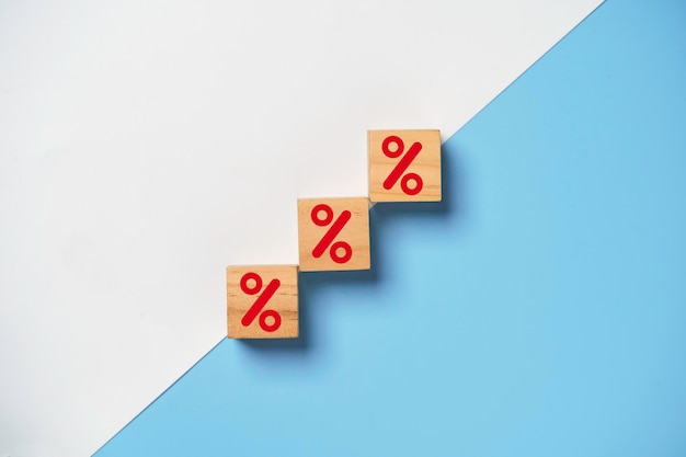 Roter Prozentzeichen-Druckbildschirm auf Holzwürfelblock auf weißem und blauem Hintergrund zur Erhöhung des Finanzzinssatzes und des Unternehmensinvestitionswachstums aus dem Dividendenkonzept