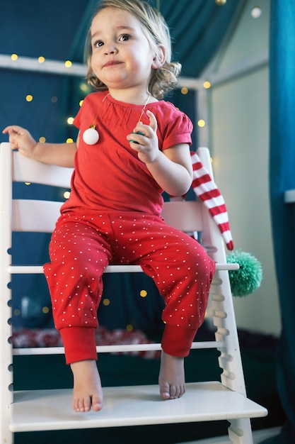 Foto roter pyjama des kindermädchens, der raumweihnachtswinterferien-silvester schmückt