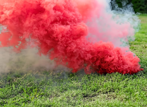 Foto roter rauch für das notfallsignal auf dem gras für die textur für den hintergrund