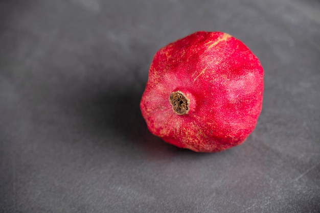 Roter reifer granatapfel auf einem dunkelgrauen hintergrund