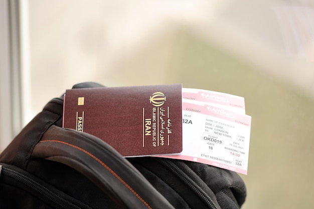Roter Reisepass der Islamischen Republik Iran mit Flugtickets auf einem touristischen Rucksack