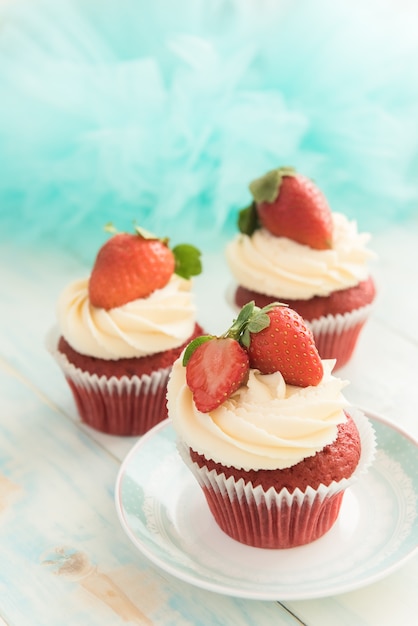 Roter Samt aus drei Cupcakes mit einer Kappe aus Frischkäse und Erdbeeren