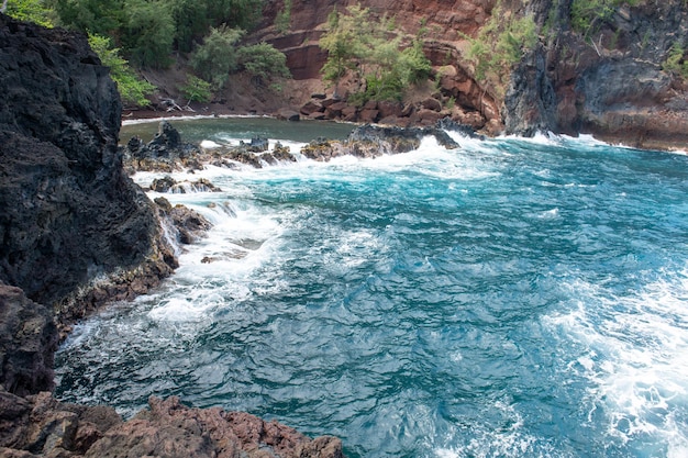 Roter Sandstrand Maui in den hawaiianischen Ozeanwellen und -felsen