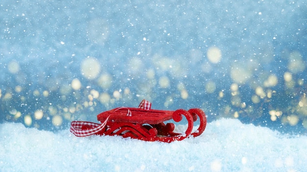 Roter Schlitten auf Schnee Festliches Bild mit goldenem Bokeh