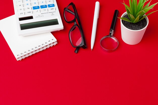 Roter Schreibtisch Tisch mit leerem Notizbuch, Tastatur und Zubehör. Draufsicht mit Kopierraum. Flach liegen.