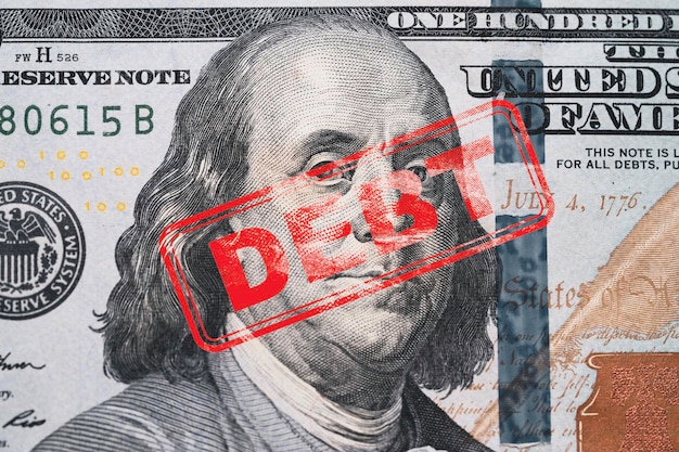 Foto roter stempel schuldenformulierung auf benjamin franklin von hundert amerikanischen usd-banknoten für die vereinigten staaten von amerika regierung schuldenobergrenze konzept