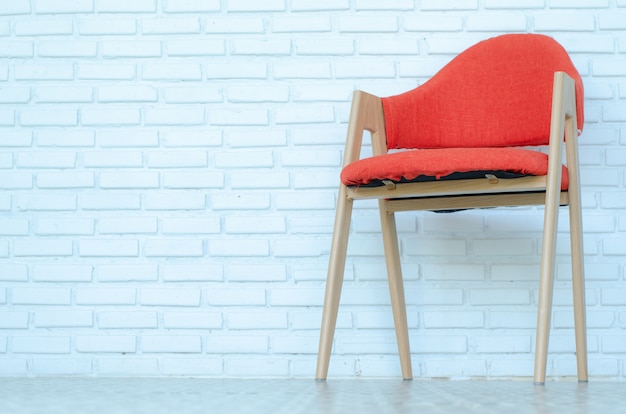 Roter Stuhl auf weißem Ziegelsteinhintergrund, moderner Raum, Kopienraum.