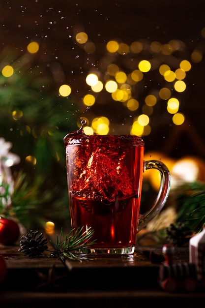 Roter Tee im Glas spritzt hoch, weil ein Sieb mit Teeblättern hineinfällt.