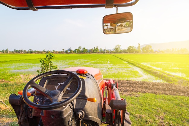 Roter Traktor auf dem landwirtschaftlichen Feld am sonnigen Sommertag