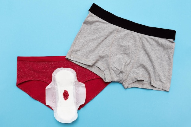 Roter Tropfen aus Perlen auf Hosen auf blauem Hintergrund Menstruationsperiode