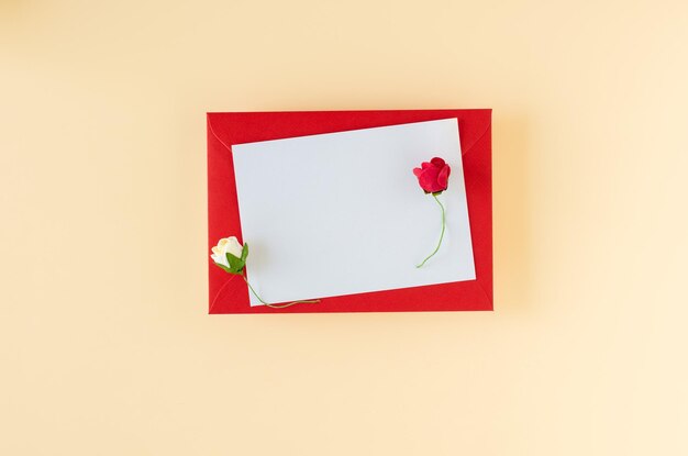 Roter Umschlag mit Karte und Rosen auf beigem Hintergrund