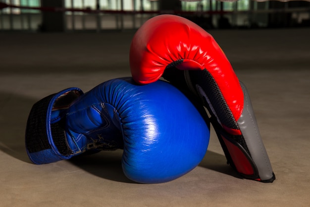 Roter und blauer Boxhandschuh auf Boxring in der Turnhalle