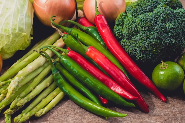 Roter und grüner Paprika und verschiedene Arten des Gemüses als Hintergrund auf Holztisch