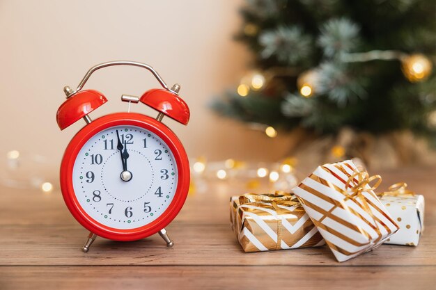 Foto roter wecker und weiße geschenkboxen mit goldenen bändern und schleife auf holzhintergrund frohe weihnachten und ein glückliches neues jahr urlaubsgrußkarte platz kopieren