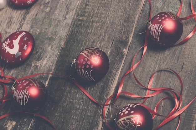 Roter Weihnachtsball und -bänder auf hölzernem Hintergrund. Neujahrskarte.