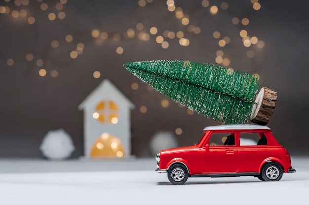 Rotes Auto mit einem Weihnachtsbaum auf dem Dach. Vor dem Hintergrund des Hauses. Konzept zum Thema Weihnachten und Neujahr.