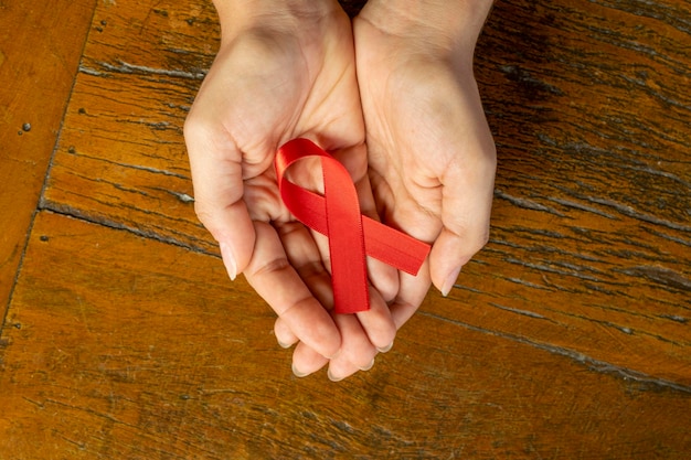 Rotes Band in den Handflächen AIDS-Präventionskampagne Roter Dezember