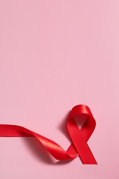 Rotes Bandsymbol des Welt-Aids-Tages auf rosa Hintergrund-Hochformat