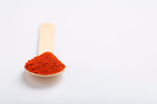 Rotes Chilipulver im Löffel auf weißer Oberfläche