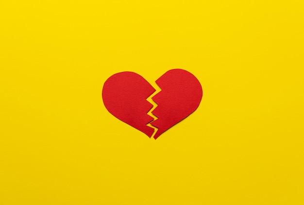 Rotes defektes Herz auf Draufsicht des gelben Hintergrundes