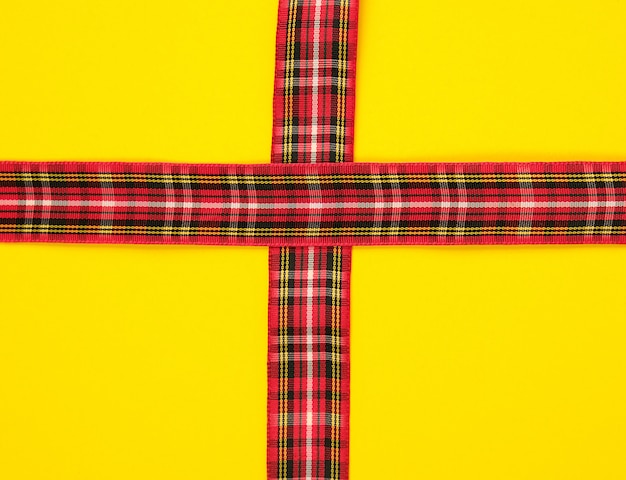 Rotes dekoratives Band in einem Kastenkreuz auf einem Kreuz