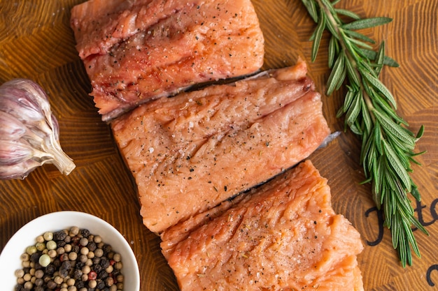 Foto rotes fischfilet mit rosmarin für steaks auf schneidebrett neben glas mit gewürzen draufsicht