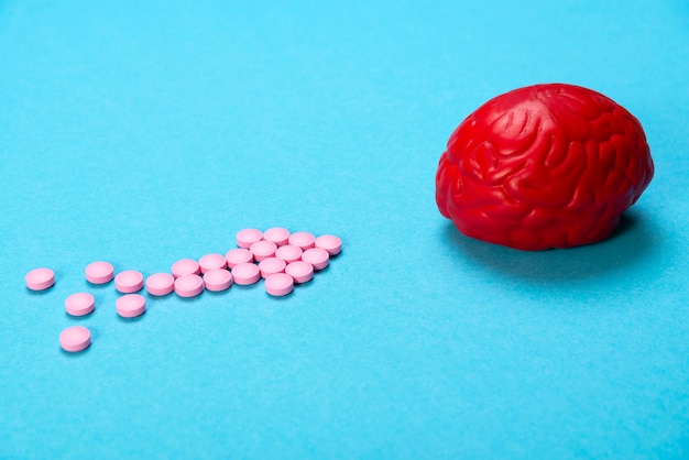 Rotes Gehirn mit rosa Pillen. Einige Pillen für das Gehirn. Drogen, Psychopharmaka, Nootropika und andere Drogen.