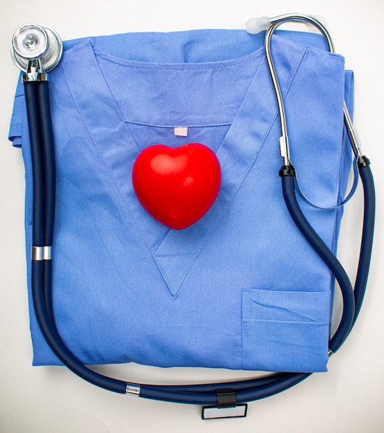 Rotes Herz auf Krankenschwesteranzug mit blauem Stethoskop. Medizinische Krankenhauskardiologie für die Pflege im Krankenhaus. Gesundes Leben.