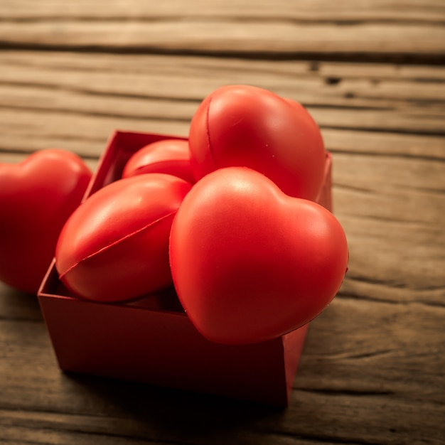 Rotes Herz in der Geschenkbox auf hölzerner Planke. Konzept für Valentinstag.