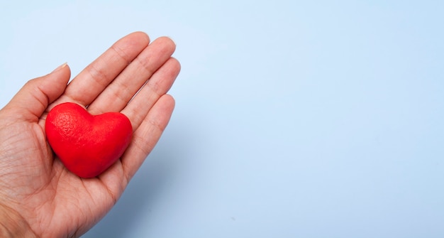 Rotes Herz in der Hand auf Blau mit Kopienraum.