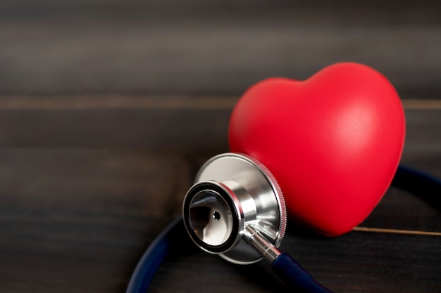 rotes Herz Liebesform und Ärzte Stethoskop auf Holztisch, Bluthochdruck oder Krankenhaus Lebensversicherung Konzept überprüfen,